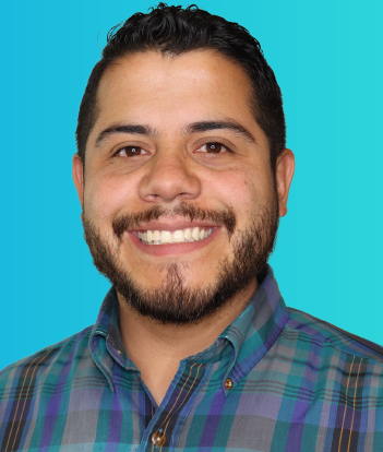 Professional portrait of a smiling man with beard wearing a plaid shirt on a blue background